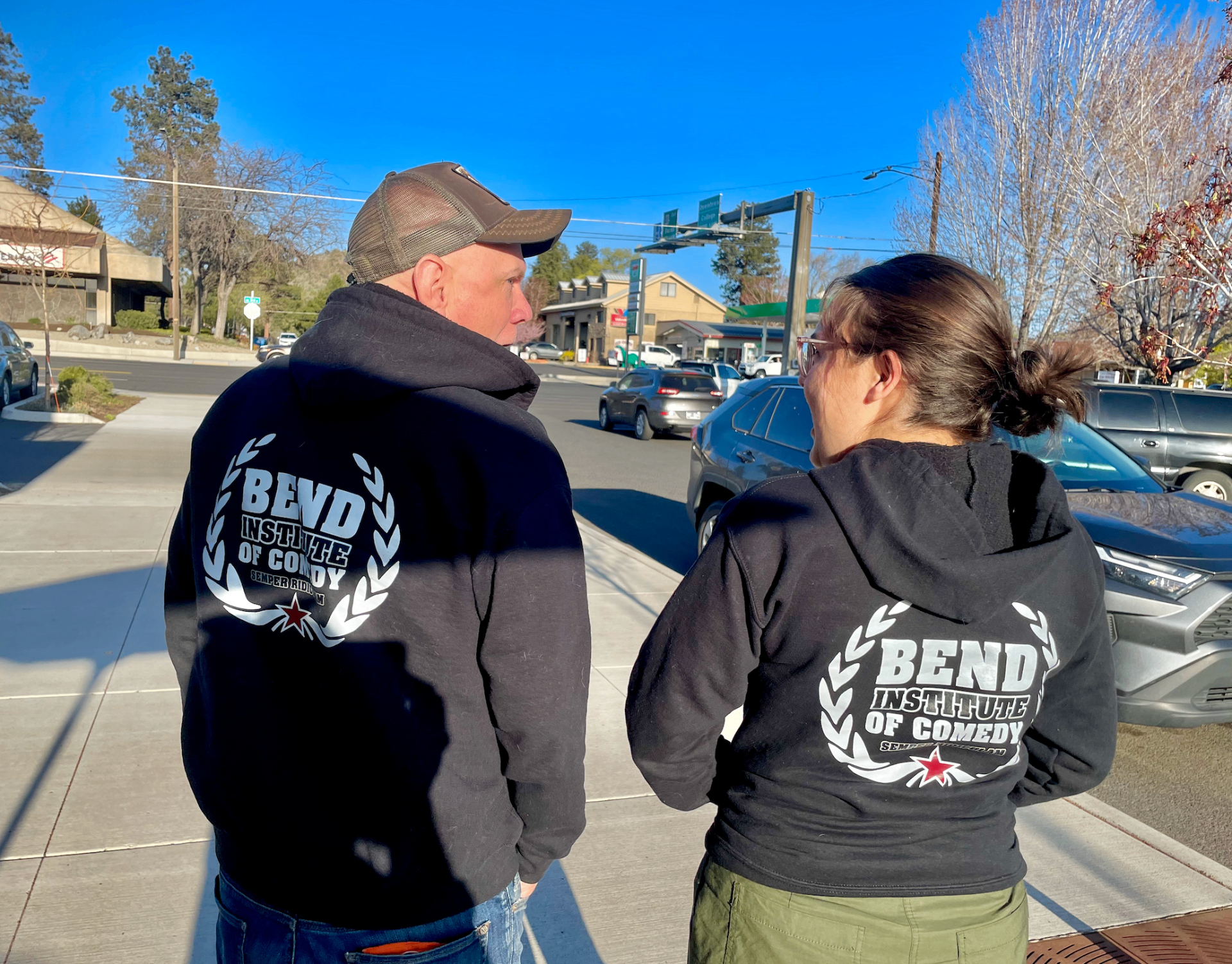Two people in BIC hoodies on a sunny Bend street