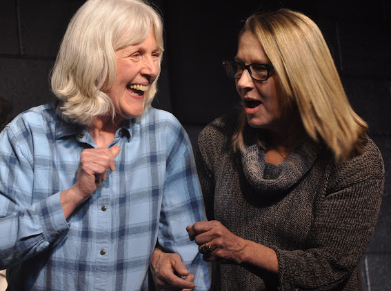 Two performers laughing together on stage